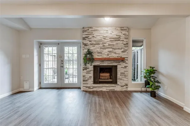 a view of an empty room with wooden floor fireplace and a window