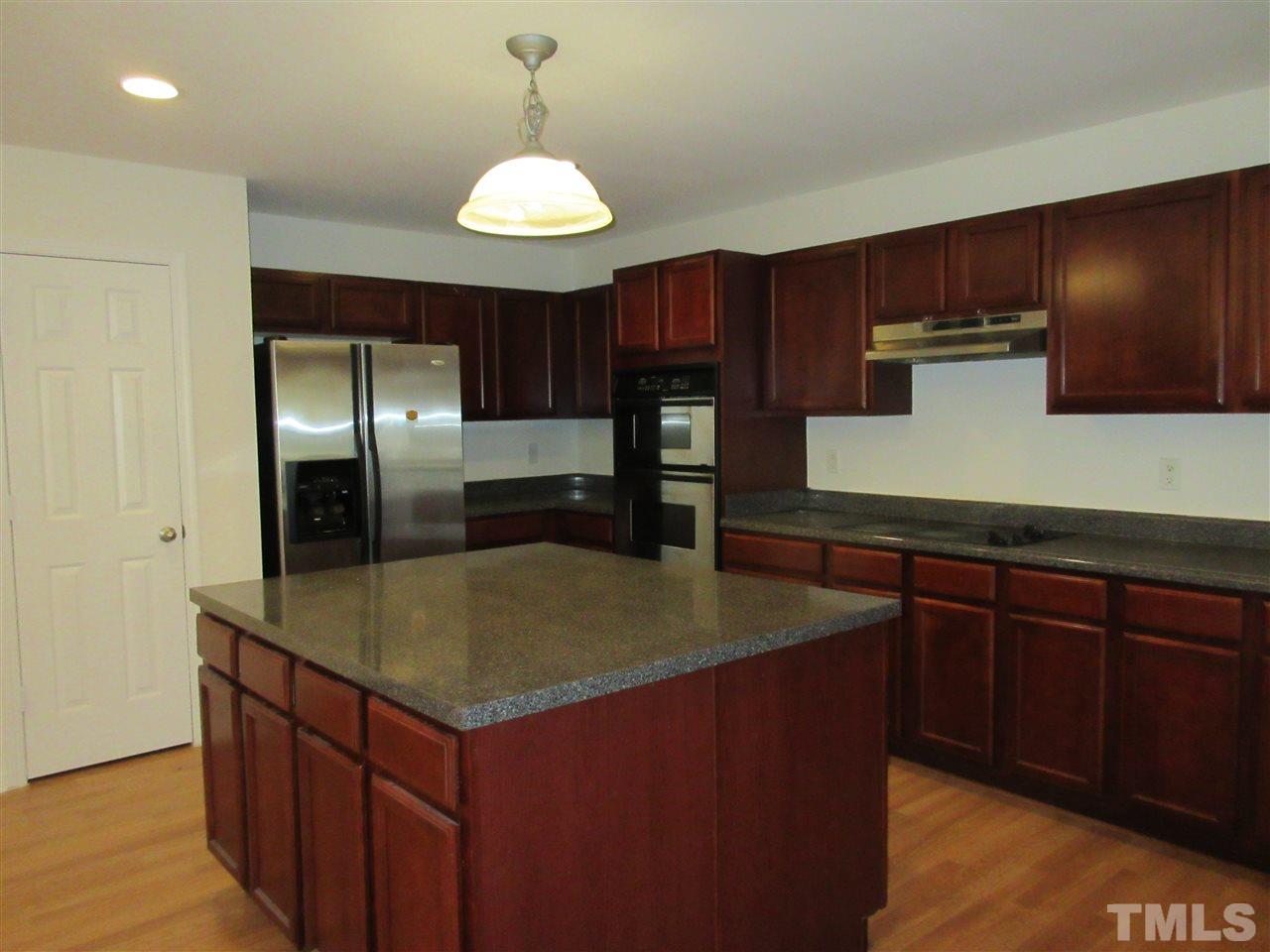 5253 Thornton Road Raleigh, NC 27616 - Photo 6 of 20 a kitchen with kitchen island granite countertop wooden cabinets a refrigerator and a sink