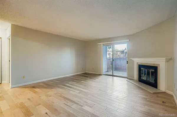 an empty room with wooden floor fireplace and windows