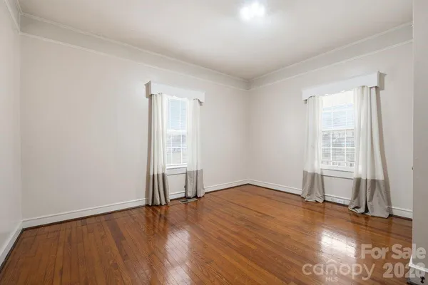 a view of an empty room with wooden floor and closet