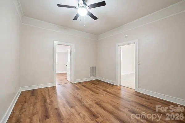 a view of empty room with wooden floor and fan