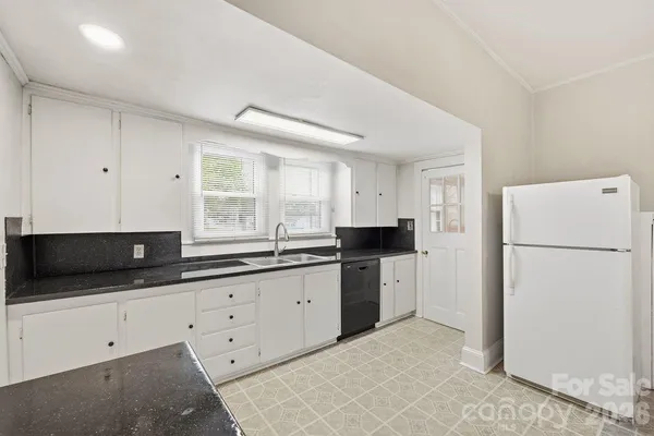 a kitchen with granite countertop white cabinets and refrigerator