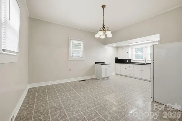 an empty room with a chandelier fan and windows