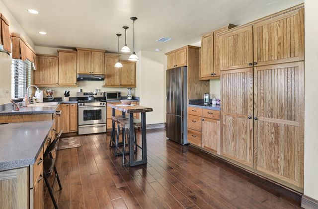 a kitchen with stainless steel appliances granite countertop a refrigerator a stove top oven a sink dishwasher and white cabinets with wooden floor