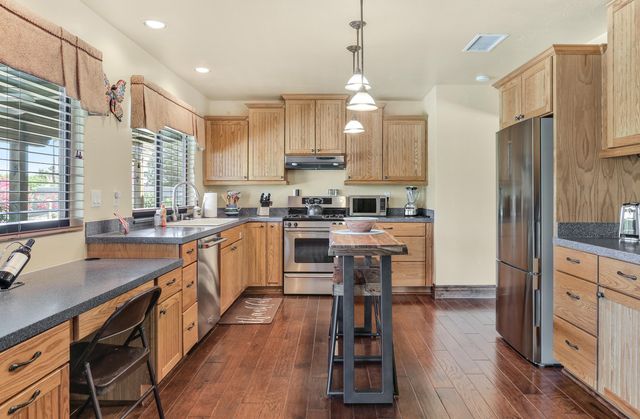 a kitchen with kitchen island granite countertop a sink a counter top space stainless steel appliances and cabinets