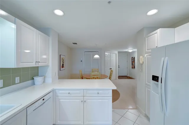 a kitchen with white cabinets and refrigerator