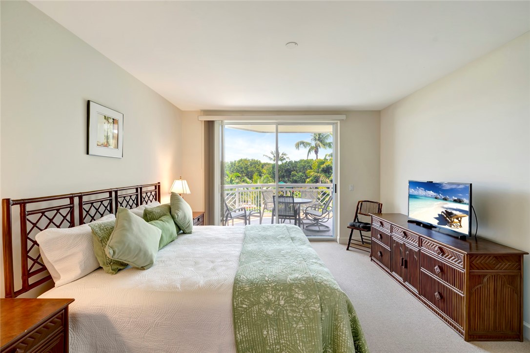 940 Turtle Cove Lane, Unit 208 Vero Beach, FL 32963 - Photo 19 of 35 a bedroom with a bed and a flat tv screen on dresser