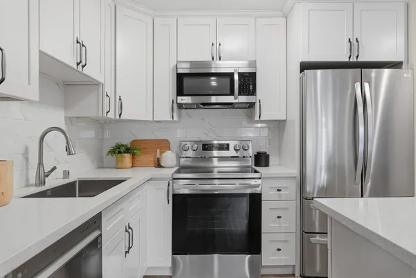 a kitchen with stainless steel appliances granite countertop a stove a refrigerator and a microwave