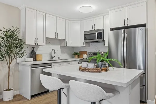 a kitchen with stainless steel appliances kitchen island granite countertop a refrigerator a stove a microwave oven with a dining table and chairs