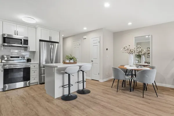 a kitchen with stainless steel appliances a dining table chairs stove refrigerator and cabinets