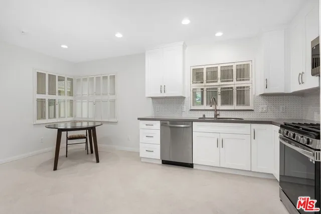 a kitchen with granite countertop a stove a sink and a refrigerator
