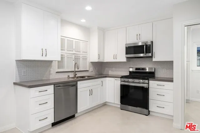 a kitchen with stainless steel appliances granite countertop a stove microwave and cabinets