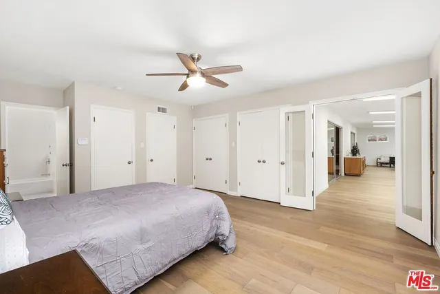 a spacious bedroom with a bed and wooden floor