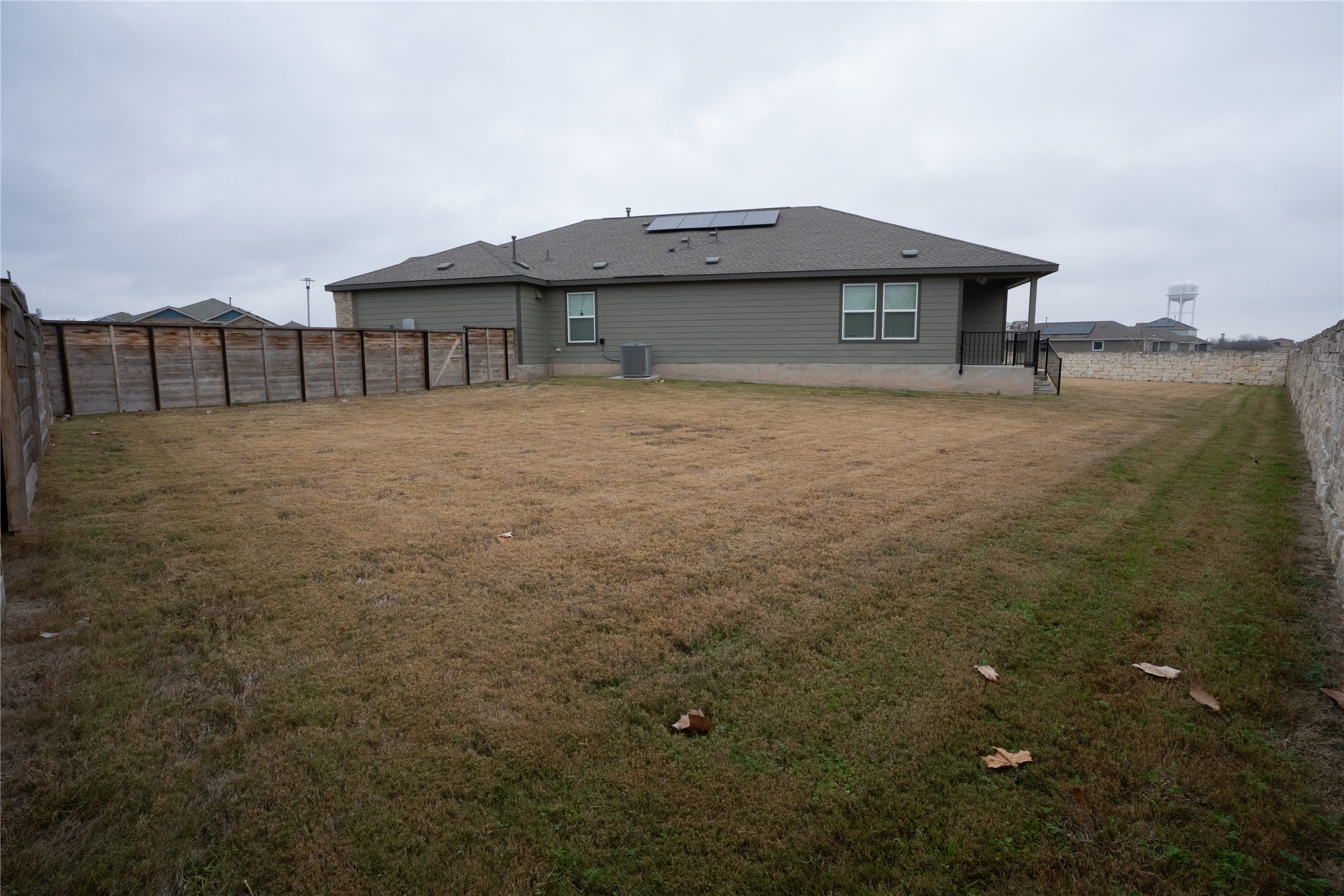 105 Carmello Kyle, TX 78640 - Photo 24 of 30 Rear view of property with roof mounted solar panels and a fenced backyard