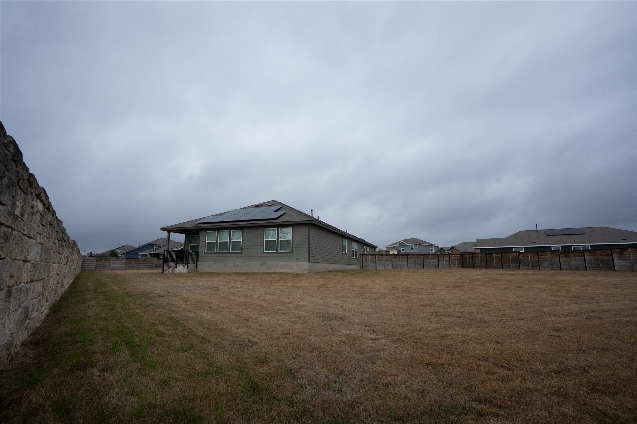 105 Carmello Kyle, TX 78640 - Photo 25 of 30 Back of property featuring roof mounted solar panels and a fenced backyard