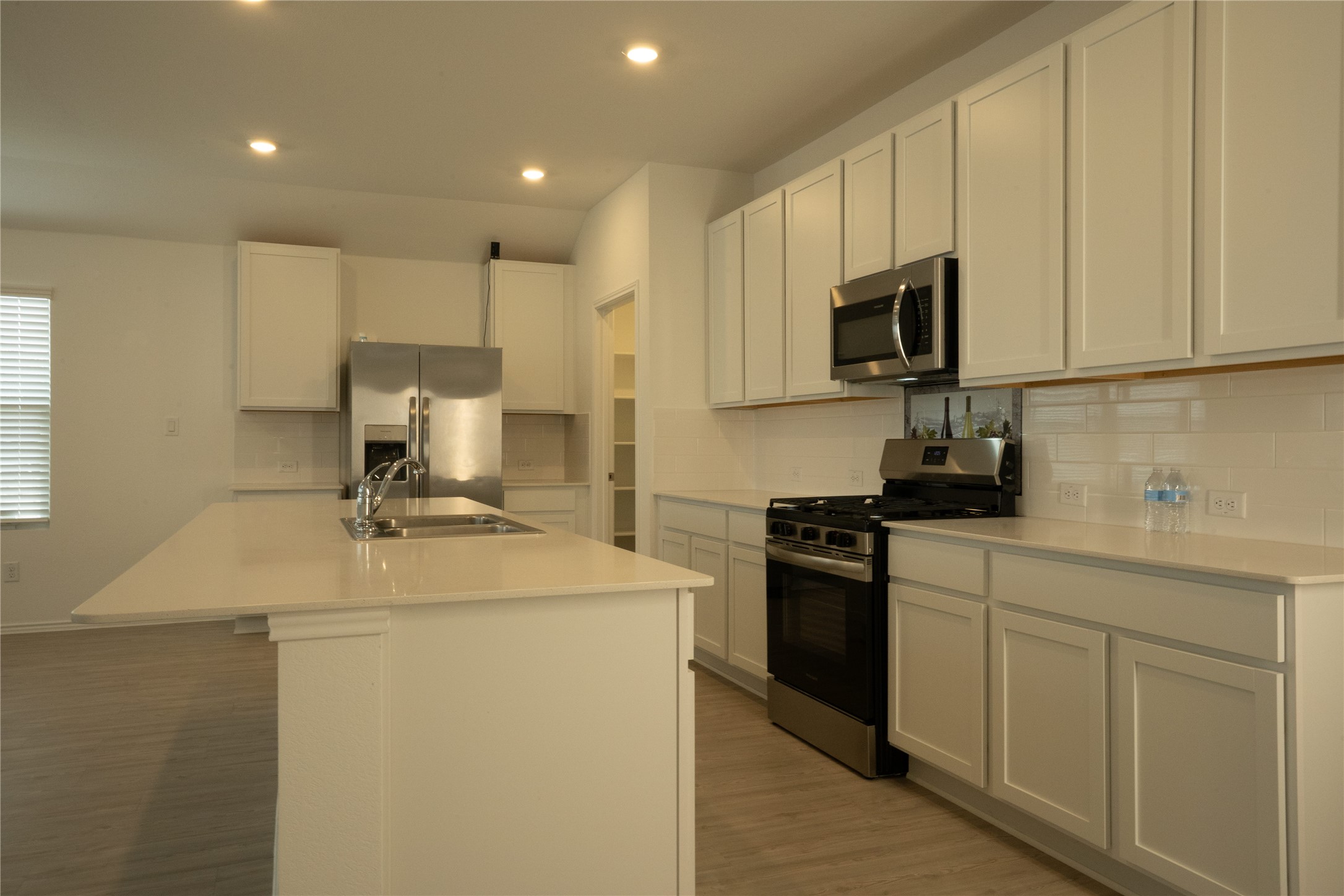 105 Carmello Kyle, TX 78640 - Photo 4 of 30 Kitchen with appliances with stainless steel finishes, recessed lighting, decorative backsplash, white cabinets, and light wood-style floors