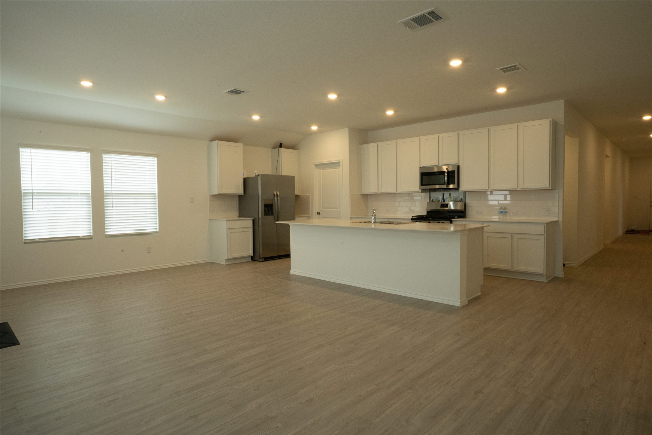 105 Carmello Kyle, TX 78640 - Photo 29 of 30 Kitchen with white cabinetry, stainless steel appliances, open floor plan, a kitchen island with sink, and recessed lighting