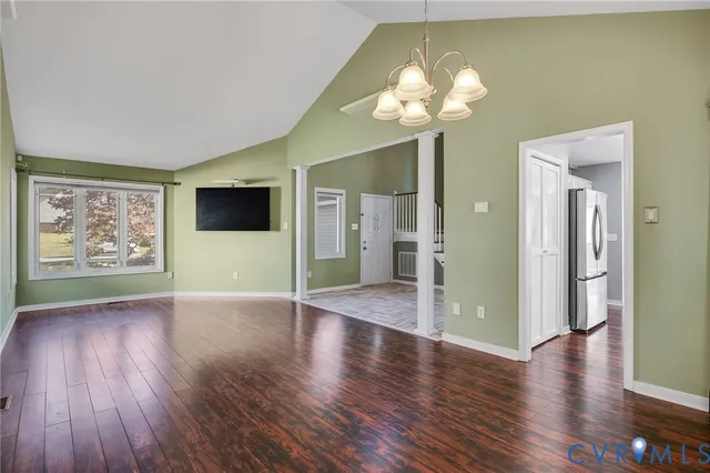 a view of an empty room with wooden floor and a large window