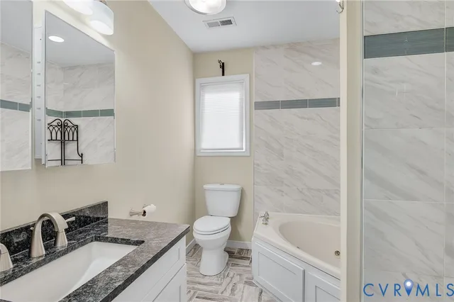 a bathroom with a granite countertop sink a toilet and bathtub