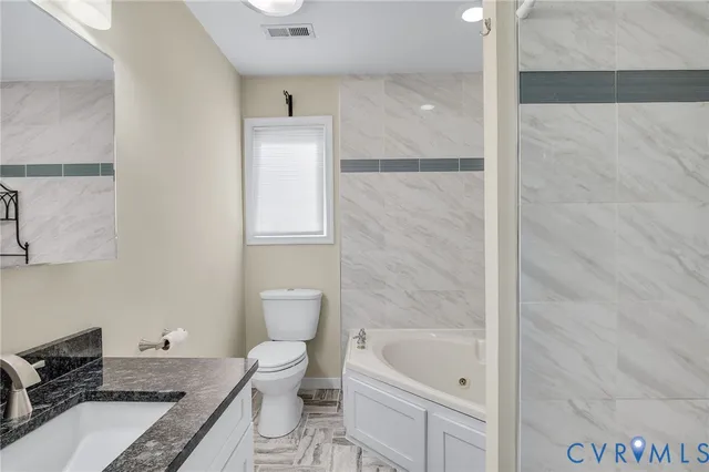 a bathroom with a granite countertop toilet a sink and bathtub