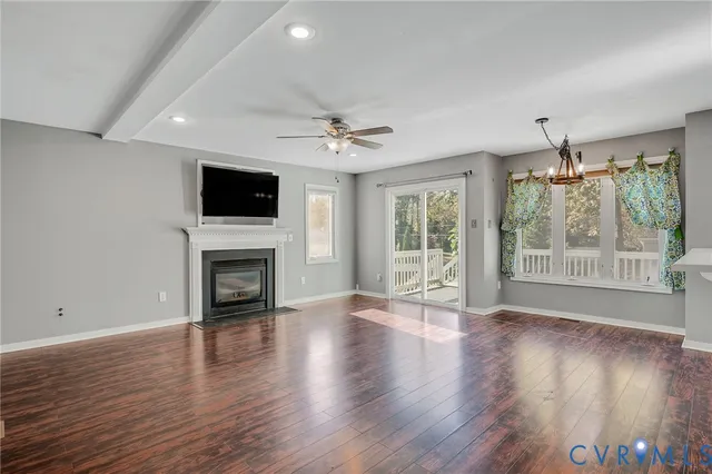 a view of an empty room with wooden floor and a fireplace