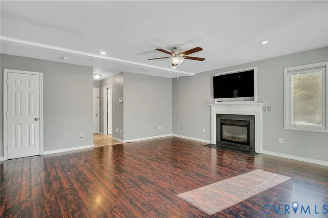 a view of a livingroom with a fireplace a ceiling fan and a kitchen view