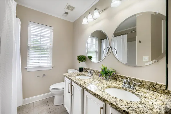 a bathroom with a granite countertop sink a toilet and a mirror
