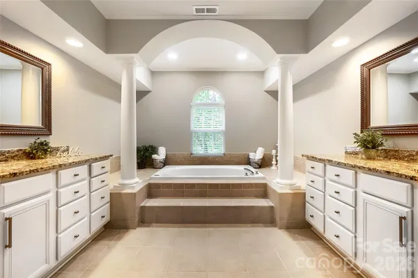 a spacious bathroom with double vanity a mirror a bathtub and double vanity