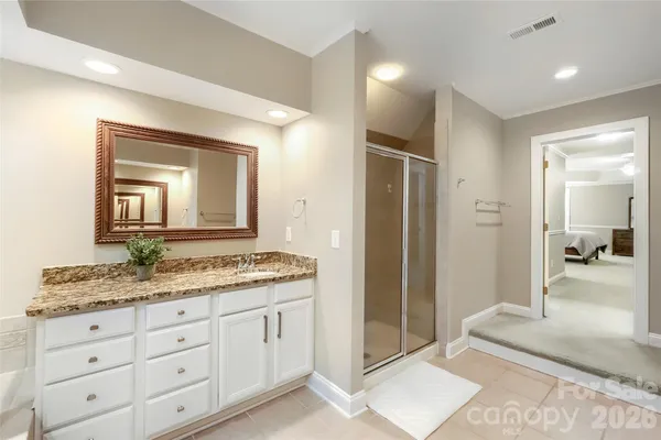 a bathroom with a granite countertop sink mirror and cabinets