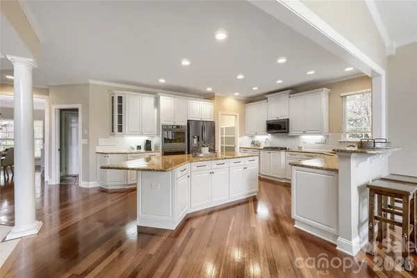 a kitchen with stainless steel appliances kitchen island granite countertop a stove a sink a refrigerator and cabinets