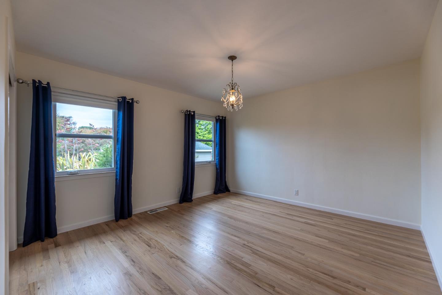 1130 Ripple Avenue Pacific Grove, CA 93950 - Photo 15 of 38 an empty room with wooden floor and windows