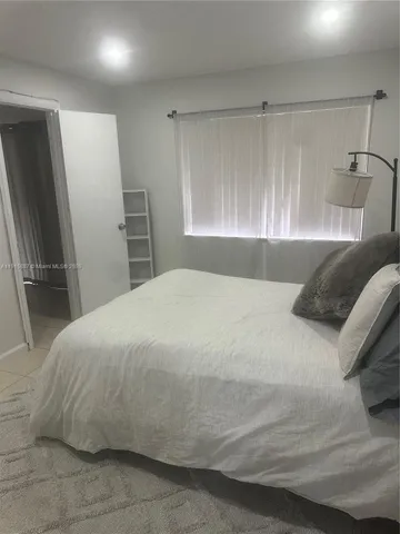 a bedroom with a bed and a refrigerator