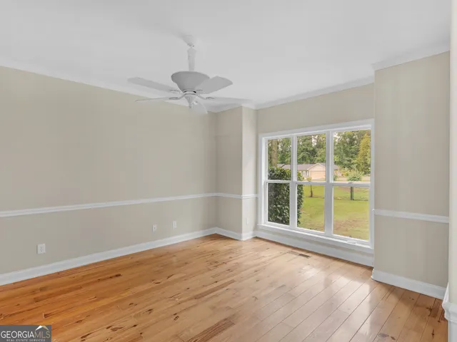 a view of an empty room with a window and wooden floor