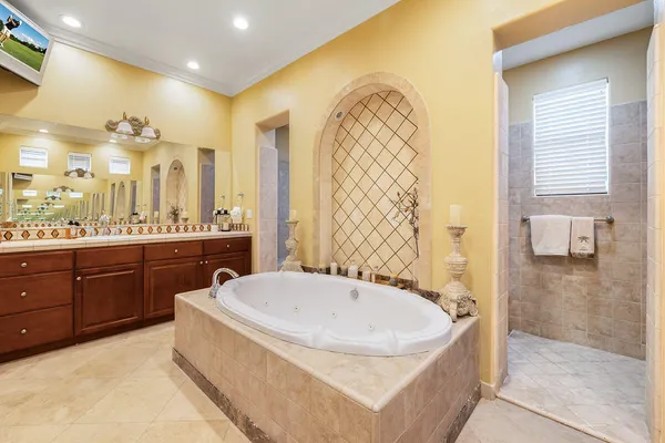 a spacious bathroom with a tub sink and mirror