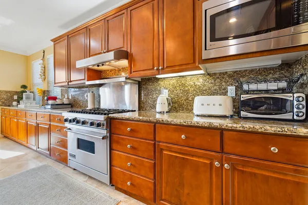 a kitchen with stainless steel appliances granite countertop a stove a sink and a microwave
