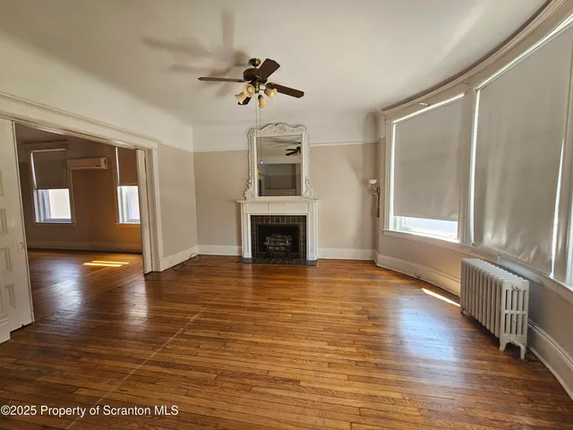 a view of a livingroom with wooden floor and a ceiling fan
