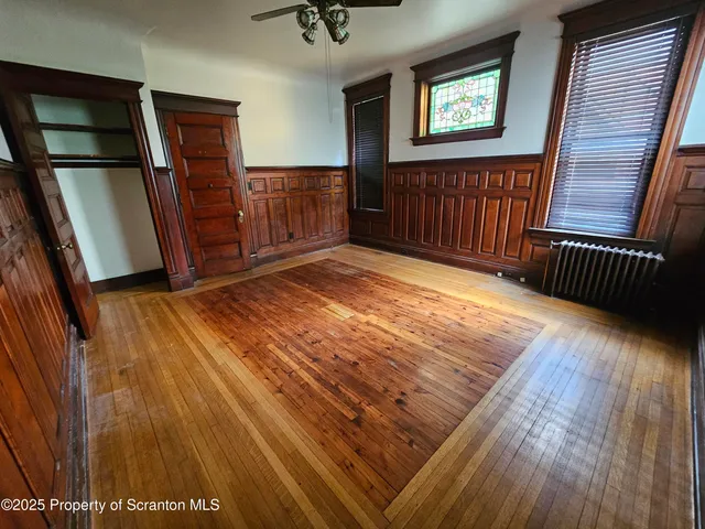 a view of an empty room with wooden floor and windows