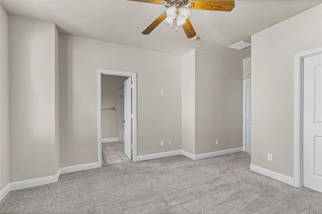 a view of an empty room and chandelier fan