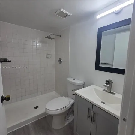 a bathroom with a toilet a sink a mirror a shower and vanity