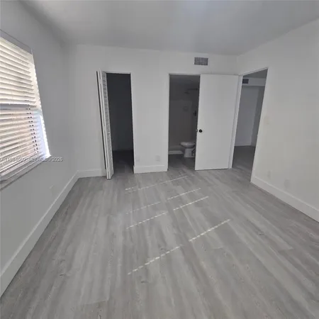 a view of an empty room with closet and a window