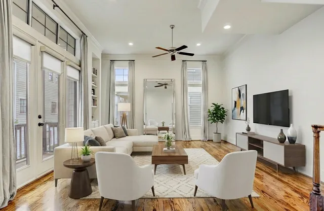 a living room with furniture a flat screen tv and a large window