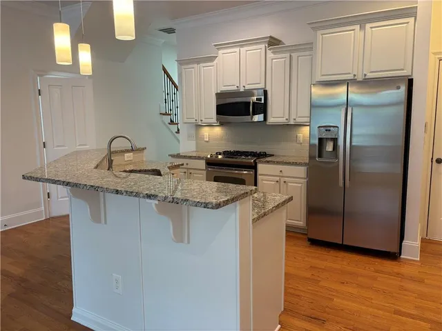 a kitchen with stainless steel appliances granite countertop a sink a stove a refrigerator a microwave a sink and cabinets