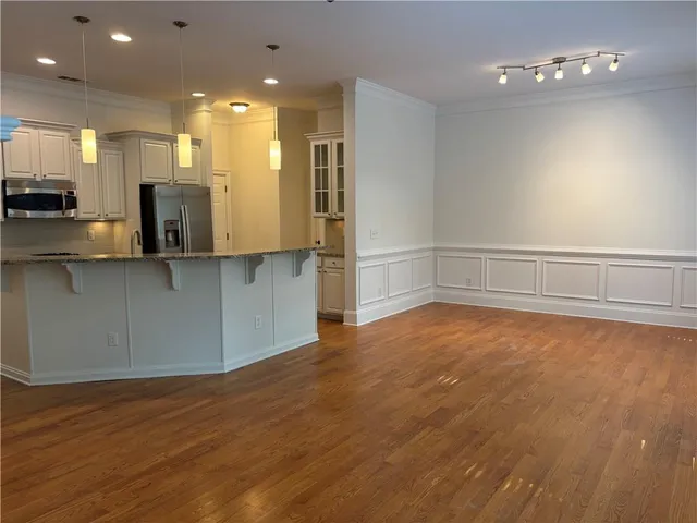a view of a kitchen with kitchen island a sink wooden floor and stainless steel appliances