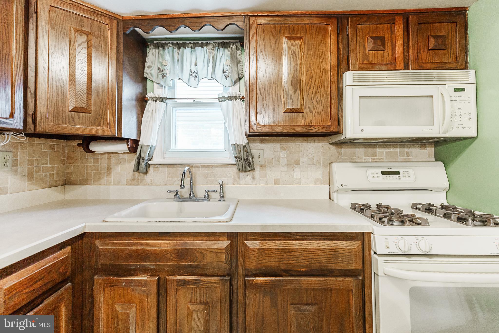 9229 Cottage Street Philadelphia, PA 19114 - Photo 6 of 14 a kitchen with a stove a sink and cabinets