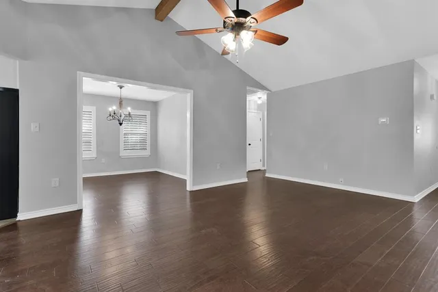 a view of an empty room with wooden floor and windows