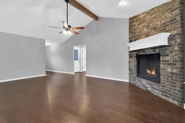 a view of an empty room with wooden floor fireplace and a window