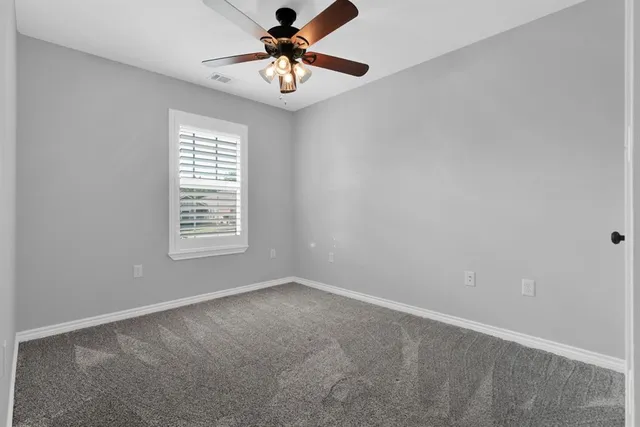 an empty room with windows and fan