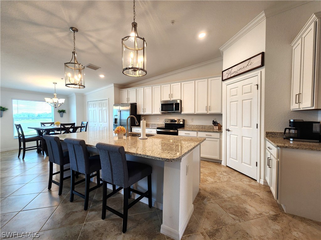 a kitchen with stainless steel appliances granite countertop a sink a stove a refrigerator cabinets and chairs