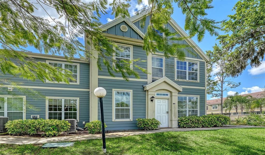 5501 Rosehill Road, Unit 105 Sarasota, FL 34233 - Photo 2 of 45 a view of a brick house with large windows and a yard with plants and large trees