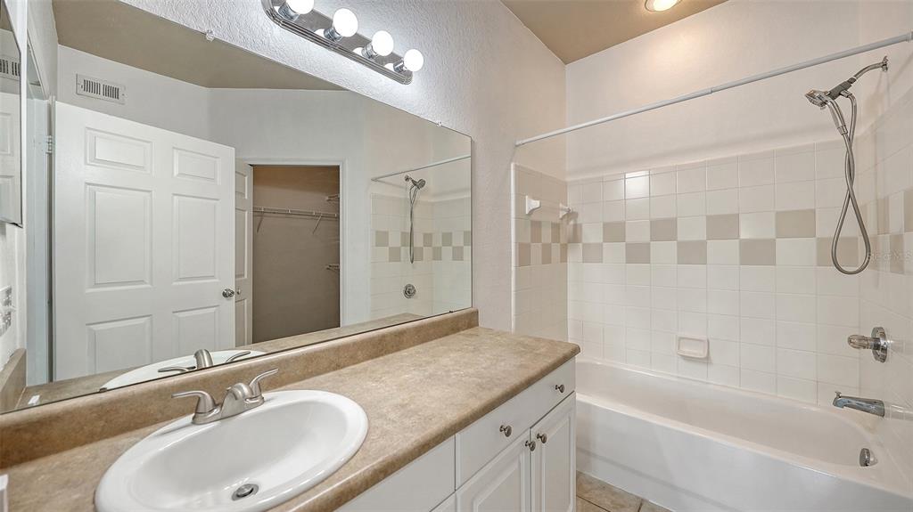 5501 Rosehill Road, Unit 105 Sarasota, FL 34233 - Photo 32 of 45 a bathroom with a granite countertop sink a mirror a shower and a bathtub